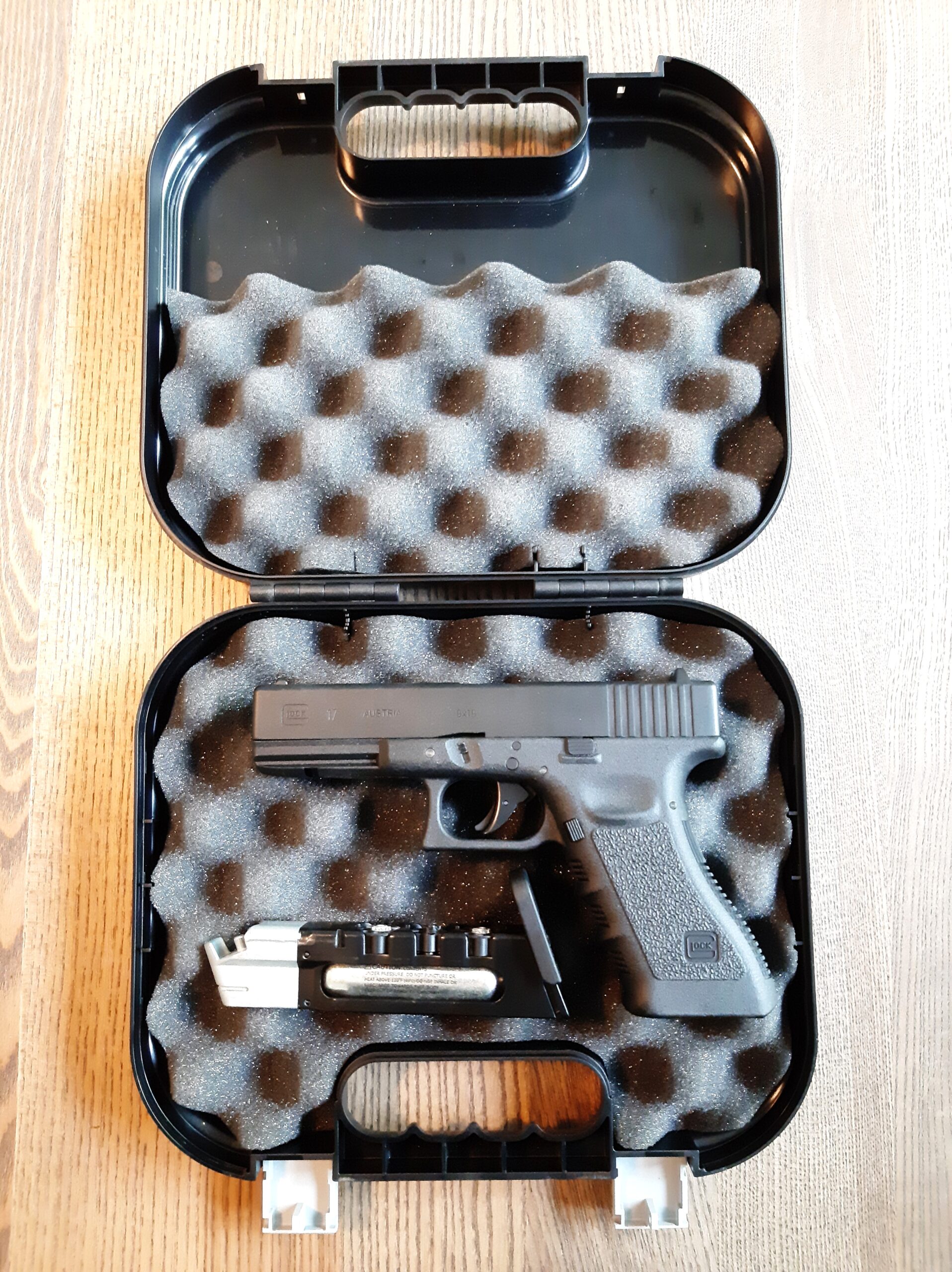 Umarex ilmapistooli laukku | Suomen Erämetsästys Open hard case revealing a black semi-automatic pistol secured in gray foam padding on a wooden surface