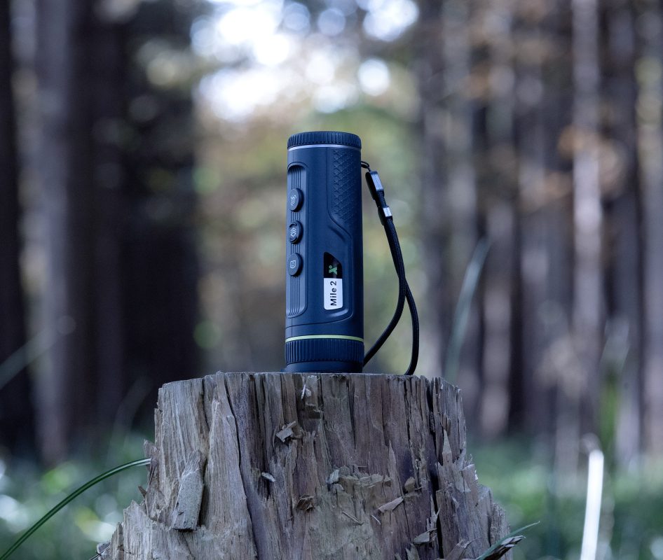 Mile2-FOREST-946x800 | Suomen Erämetsästys Blue rugged flashlight with a wrist strap standing upright on a weathered tree stump in a forest setting.